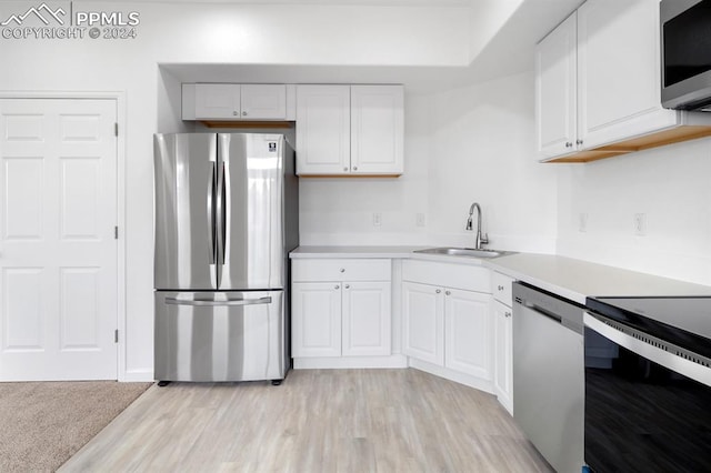 kitchen with light hardwood / wood-style flooring, white cabinets, appliances with stainless steel finishes, and sink