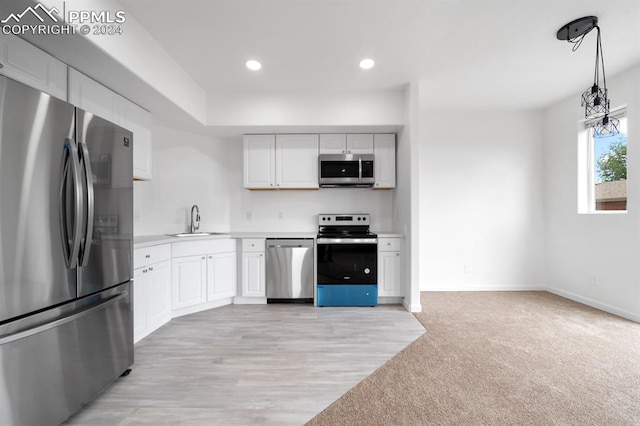 kitchen featuring white cabinets, decorative light fixtures, appliances with stainless steel finishes, light carpet, and sink