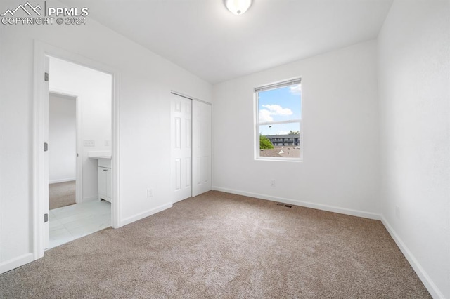 unfurnished bedroom with light carpet and a closet