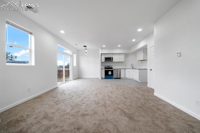 unfurnished living room with light colored carpet and sink