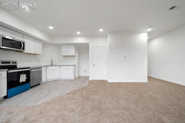 kitchen with white cabinets, stainless steel appliances, light carpet, and sink