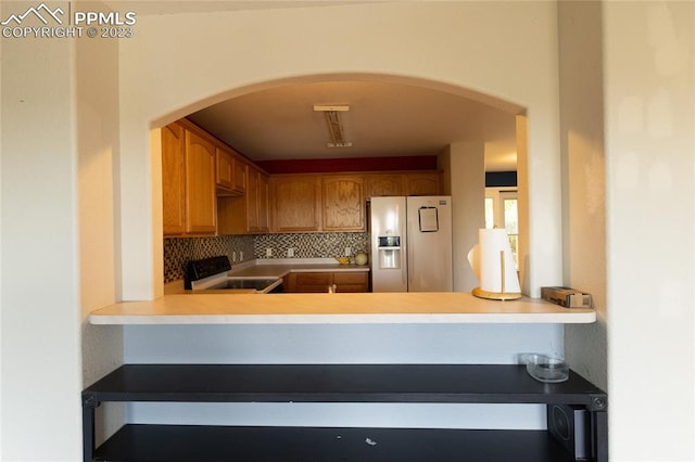 kitchen with white refrigerator with ice dispenser, range, and backsplash