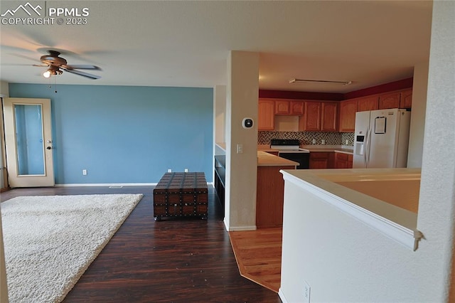 kitchen with ceiling fan, electric range, dark wood-type flooring, white fridge with ice dispenser, and tasteful backsplash