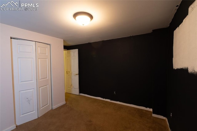 unfurnished bedroom with dark carpet and a closet