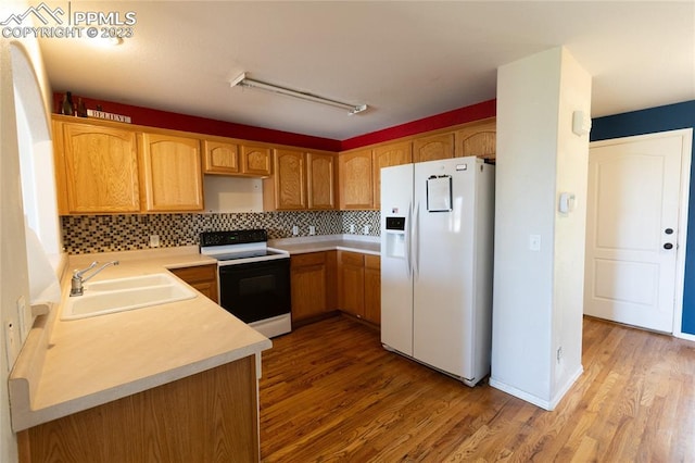 kitchen with light hardwood / wood-style flooring, tasteful backsplash, white appliances, and sink