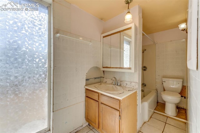 full bathroom featuring toilet, tile floors, vanity, and tile walls