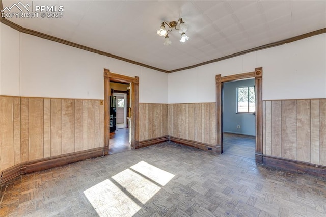 spare room featuring a notable chandelier, parquet flooring, and crown molding