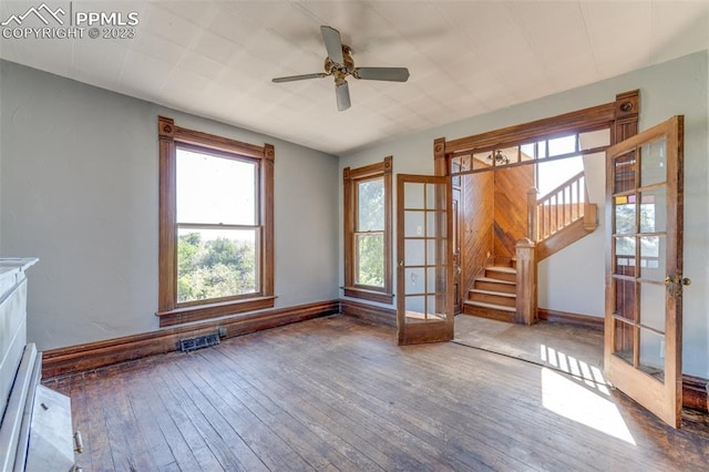 spare room with ceiling fan, a baseboard heating unit, french doors, and hardwood / wood-style flooring