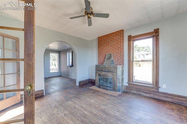 unfurnished living room with ceiling fan, dark wood-type flooring, and a wealth of natural light