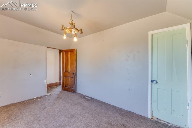 unfurnished bedroom with a notable chandelier, carpet floors, and vaulted ceiling