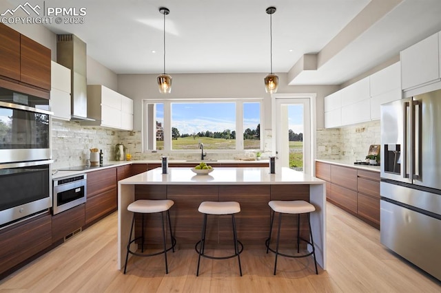 kitchen with a kitchen island, appliances with stainless steel finishes, tasteful backsplash, and white cabinetry