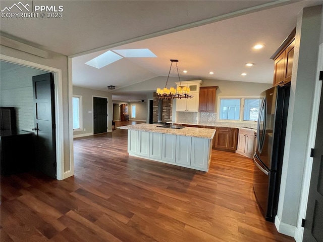 kitchen featuring light stone countertops, decorative light fixtures, dark wood-type flooring, a center island, and stainless steel refrigerator