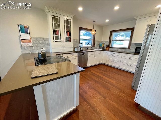 kitchen featuring dark hardwood / wood-style floors, pendant lighting, backsplash, white cabinets, and appliances with stainless steel finishes