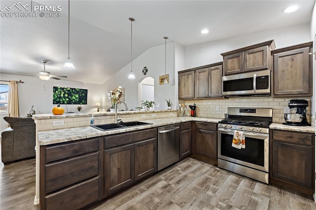 kitchen with kitchen peninsula, ceiling fan, appliances with stainless steel finishes, light hardwood / wood-style floors, and sink