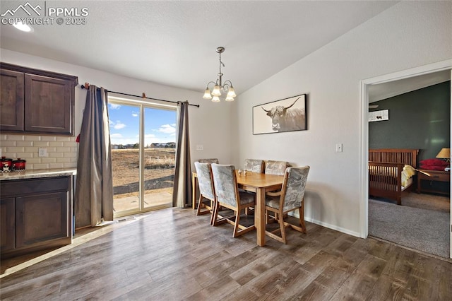 carpeted dining area featuring a chandelier and lofted ceiling