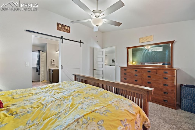 carpeted bedroom with connected bathroom, sink, ceiling fan, a barn door, and lofted ceiling