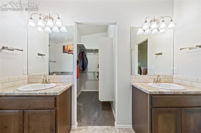 bathroom featuring tile flooring, oversized vanity, vaulted ceiling, and dual sinks