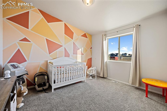 bedroom with a crib and dark colored carpet