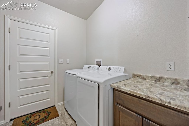 clothes washing area with hookup for a washing machine, washer and clothes dryer, cabinets, and light tile floors