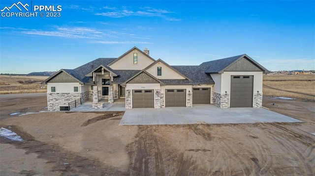 view of front facade featuring stone siding, concrete driveway, and stucco siding