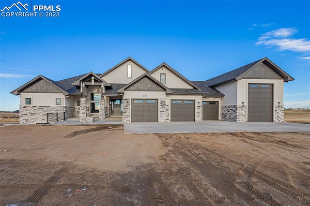 view of front of house featuring concrete driveway, stone siding, and stucco siding