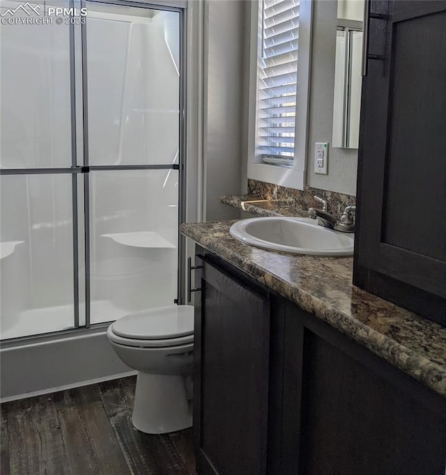 bathroom featuring vanity, hardwood / wood-style flooring, a shower with door, and toilet