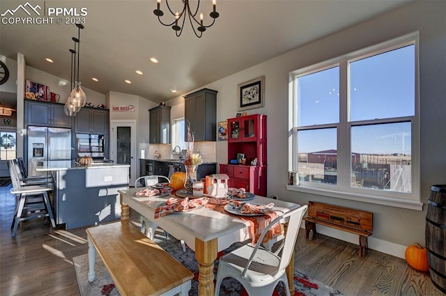 dining area with vaulted ceiling, a notable chandelier, dark hardwood / wood-style floors, and sink