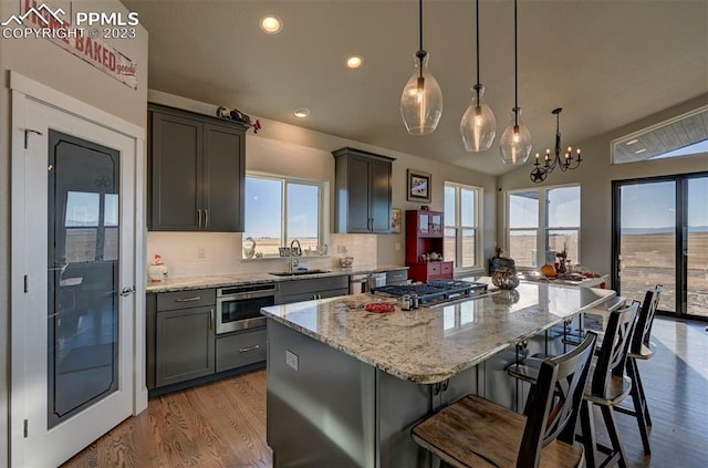 kitchen with a kitchen island, a chandelier, a healthy amount of sunlight, and light hardwood / wood-style floors