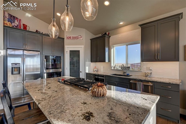 kitchen with appliances with stainless steel finishes, sink, a center island, light stone counters, and a breakfast bar area