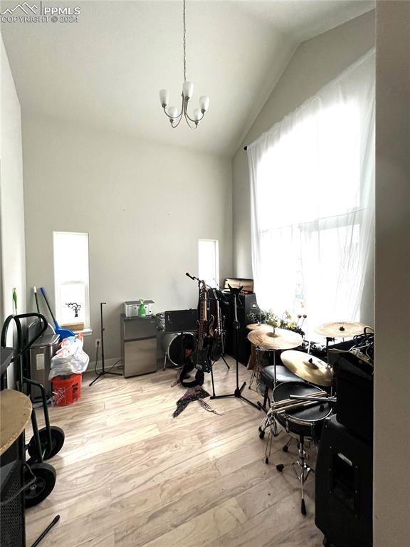 office with vaulted ceiling, a chandelier, and light wood-type flooring