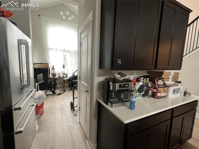 kitchen with a notable chandelier, dark brown cabinetry, light wood-type flooring, and high end fridge