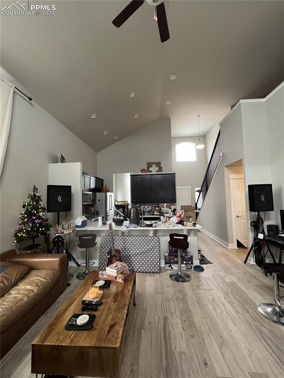 living room with high vaulted ceiling, light wood-type flooring, and ceiling fan