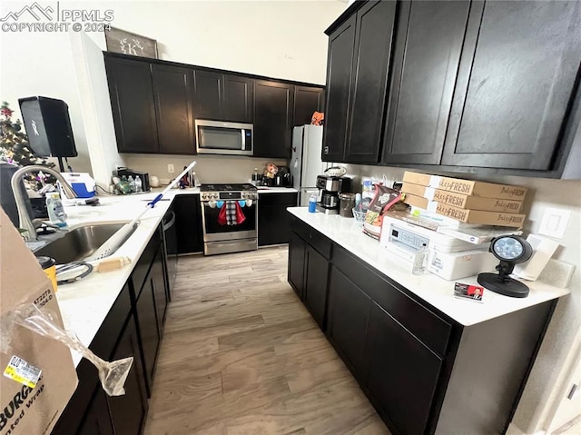 kitchen featuring stainless steel appliances, sink, and light wood-type flooring