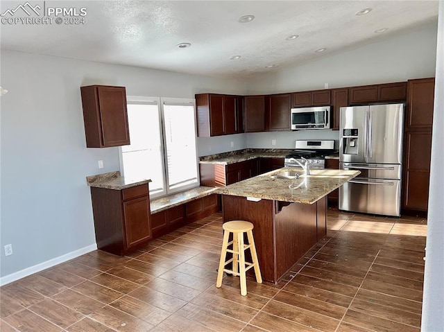 9785 N Calhan Hwy, Calhan, CO 80808 - kitchen featuring a breakfast bar area, lofted ceiling, a kitchen island with sink, a sink, and appliances with stainless steel finishes