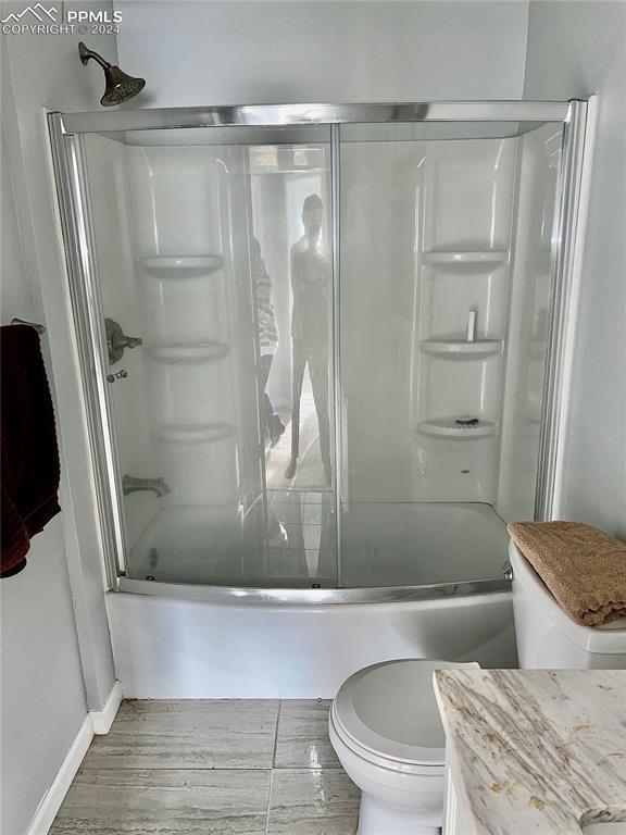 9785 N Calhan Hwy, Calhan, CO 80808 - bathroom featuring baseboards, toilet, wood finished floors, combined bath / shower with glass door, and vanity