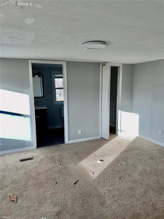 9785 N Calhan Hwy, Calhan, CO 80808 - carpeted empty room with visible vents, a textured ceiling, and baseboards