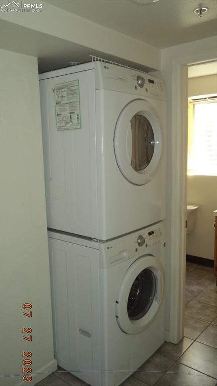 clothes washing area featuring stacked washing maching and dryer and light tile patterned floors