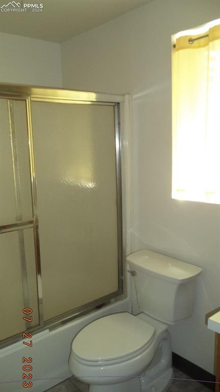 full bathroom with vanity, bath / shower combo with glass door, toilet, and tile patterned flooring