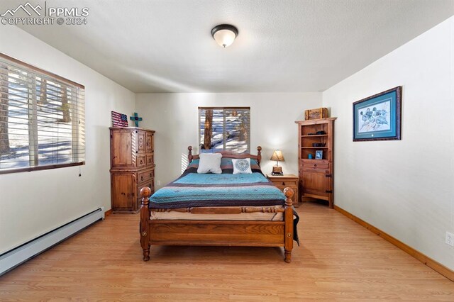 bedroom featuring a baseboard radiator and light hardwood / wood-style floors