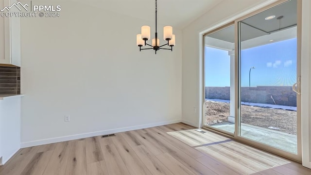 unfurnished dining area featuring light hardwood / wood-style floors, an inviting chandelier, and plenty of natural light