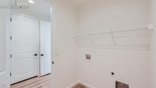 washroom featuring hookup for a washing machine, electric dryer hookup, and light hardwood / wood-style flooring