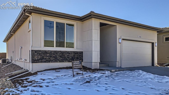 view of front of property with a garage and central AC