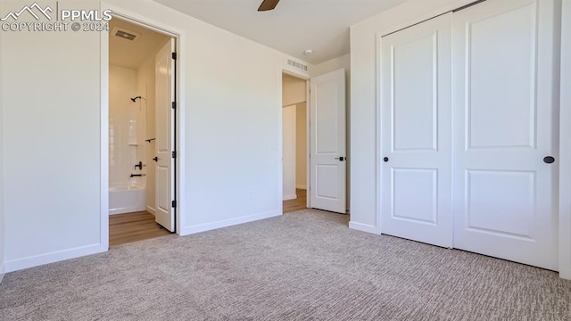 unfurnished bedroom featuring a closet, carpet, ensuite bathroom, and ceiling fan