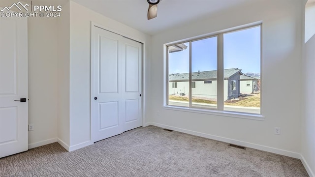 unfurnished bedroom featuring ceiling fan, a closet, and carpet flooring