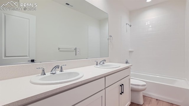 full bathroom featuring dual vanity, hardwood / wood-style floors, shower / bathtub combination, and toilet