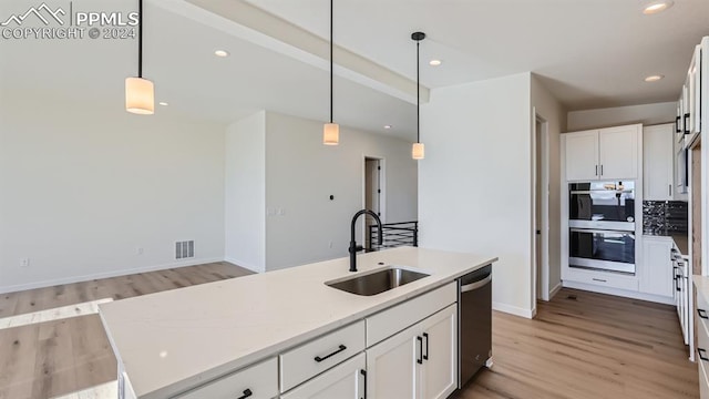 kitchen with light hardwood / wood-style flooring, stainless steel appliances, sink, an island with sink, and white cabinetry