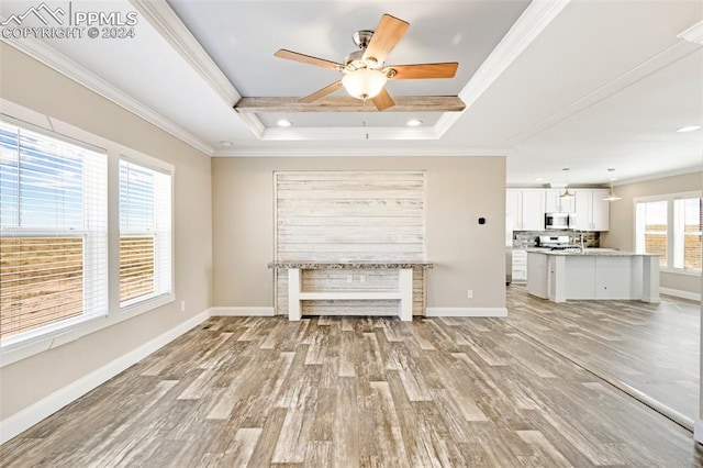 unfurnished living room with ceiling fan, crown molding, light hardwood / wood-style flooring, and a raised ceiling