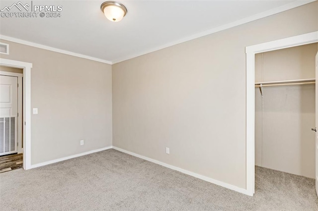 unfurnished bedroom featuring a closet, light carpet, a spacious closet, and ornamental molding