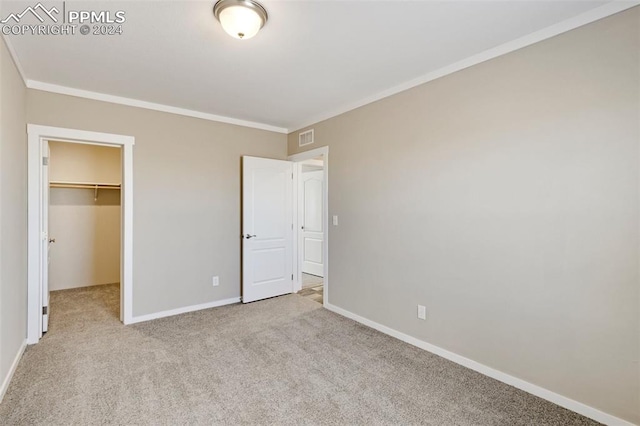 unfurnished bedroom featuring light carpet, a spacious closet, a closet, and ornamental molding