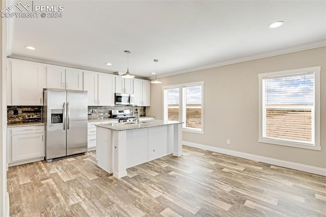 kitchen featuring pendant lighting, backsplash, stainless steel appliances, light stone countertops, and white cabinetry